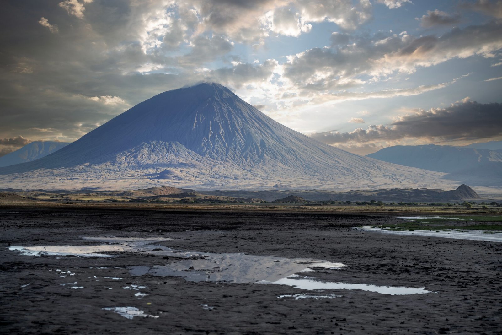 A stunning mountain landscape, featuring a volcano under a dramatic cloudy sky.