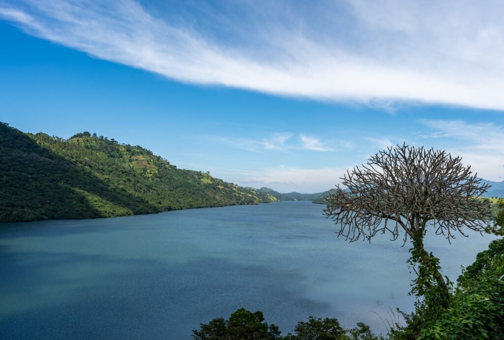 Serene view of a tropical lake with lush hillside and blue sky, perfect for travel inspiration.